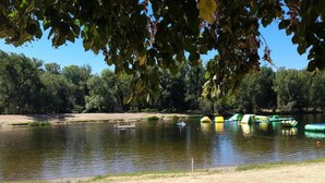 Un lac avec des bateaux, une plage de sable et des arbres en arrière-plan.