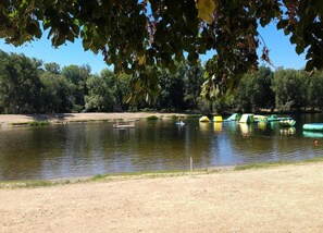 A lake with boats, a sandy shore, and trees in the background. - Nature Escape in Loubressac With Pool (Loubressac)