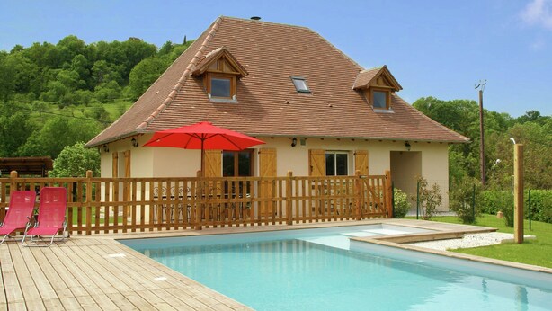 Une maison avec une piscine, une terrasse en bois et un parasol rouge.