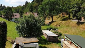 Un paysage rural avec un petit bâtiment doté d’un toit en pente, entouré de verdure et d’arbres.