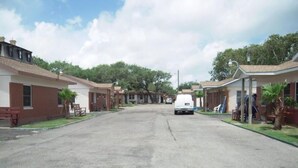 A street lined with single-story buildings, each with a porch and a small garden. - Bayfront Cottage Room 11 (Rockport)