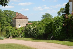 A rustic stone building with a red-tiled roof, surrounded by lush greenery and flowering bushes. - Mansion in Champvert With Pond View Terrace (Champvert)
