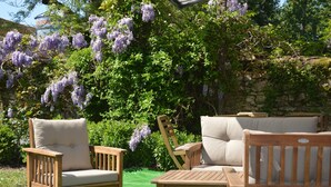 Un jardín con mobiliario de madera y flores púrpuras.