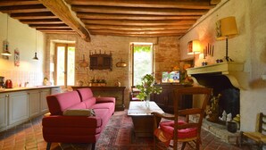 Un interior rústico con un sofá rojo, una mesa de madera y una chimenea.