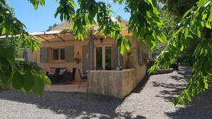 Ein Haus mit Terrasse, Essbereich und einer Steinmauer.