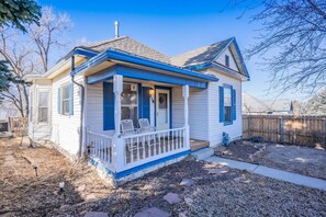 A single-story house with a porch, a chimney, and a fenced backyard.