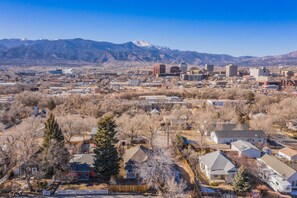 Un quartier résidentiel avec des maisons, quelques arbres et une vue lointaine sur une ville entourée de montagnes.