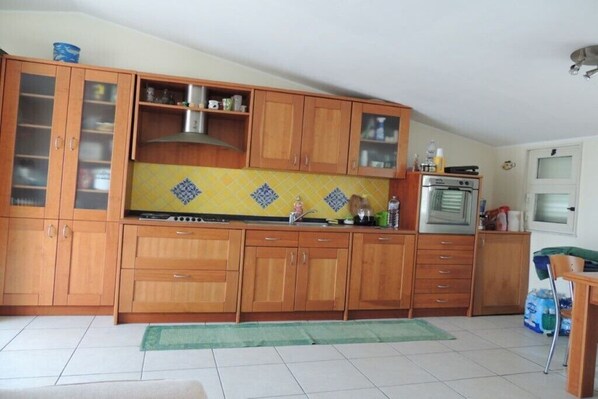 A kitchen with wooden cabinets, a stove, and a tiled backsplash.