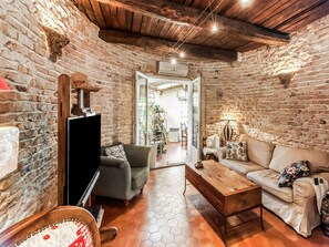 A rustic living room with stone walls, a wooden ceiling, a sofa, a coffee table, and a TV. - Holiday Home in Lorgues With Pool and Terrace (Lorgues)