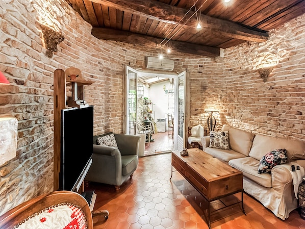 A rustic living room with stone walls, a wooden ceiling, a sofa, a coffee table, and a TV. - Holiday Home in Lorgues With Pool and Terrace (Lorgues)