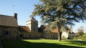 A stone building with a tower, a large tree in the foreground, and a clear sky. - Cottage in Wierre-effroy Near Forest (Wierre-Effroy)
