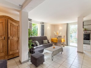 A living room with a sofa, ottoman, dining table, and chairs. - Cozy Hillside Escape in Berre (Berre-des-Alpes)