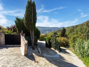 A gravel driveway leading to a gated entrance with a view of a mountainous landscape. - Cozy Hillside Escape in Berre (Berre-des-Alpes)