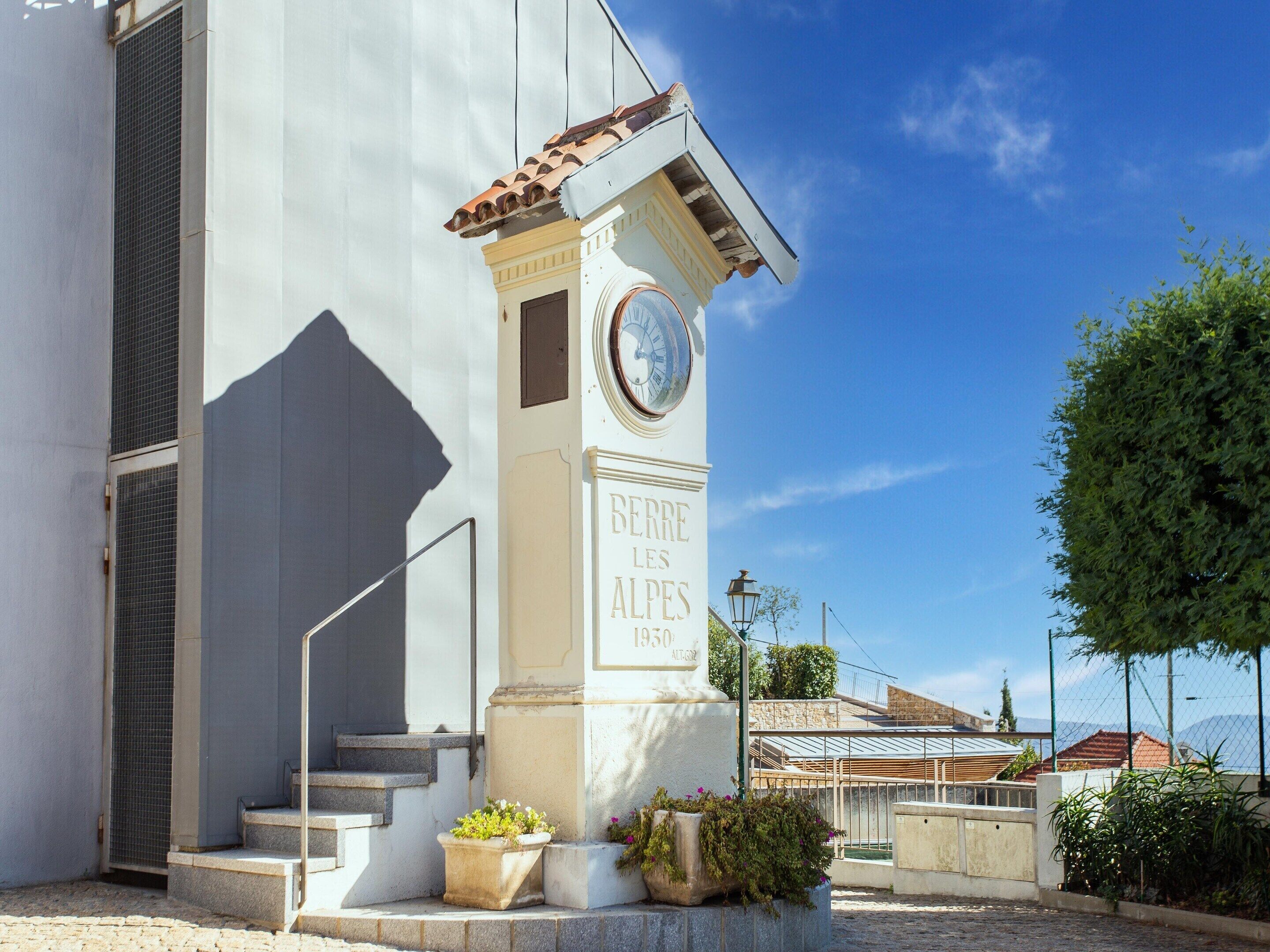 A building with a clock tower, steps leading up to it, and a plaque reading 'BERRE LES ALPES 1950 AUT. 532'.