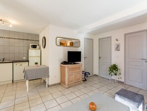 A compact living space with a kitchenette, a dining area, a television, and a mirror. - Cozy Hillside Escape in Berre (Berre-des-Alpes)