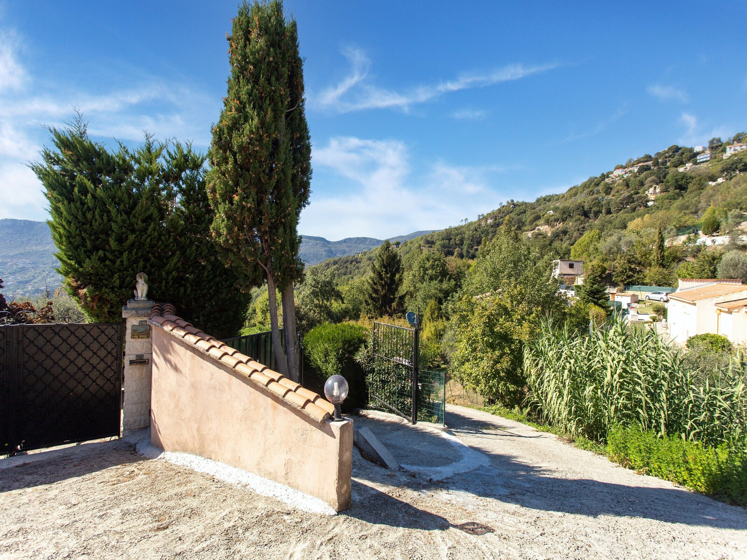 A gated entrance with a clear view of a mountainous landscape and residential buildings.