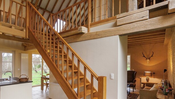 A spacious interior with a wooden staircase, a kitchen area, a dining space, and a living room. - Beautifully Located Country House With Heated Pool (Auriac)