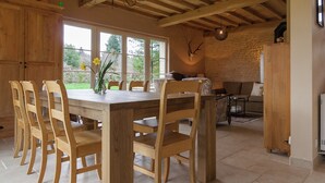 A wooden dining table with chairs, a chandelier, and a stone wall with a mounted animal skull. - Beautifully Located Country House With Heated Pool (Auriac)