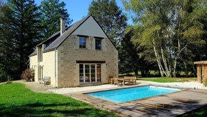 A stone house with a swimming pool, wooden deck, and outdoor furniture. - Beautifully Located Country House With Heated Pool (Auriac)