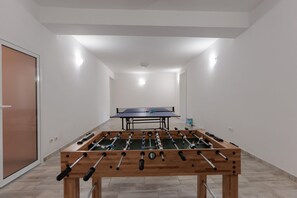 A room with a foosball table, a ping pong table, and a door. - Holiday Home in Galovac With Pool (Galovac)