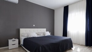Um quarto com uma cama, mesas de cabeceira e uma janela com cortinas.