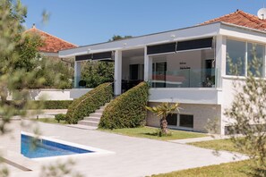 A modern two-story house with a swimming pool, a covered patio, and a well-maintained garden. - Holiday Home in Galovac With Pool (Galovac)
