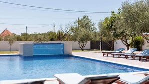 Uma piscina com espreguiçadeiras e um ofurô.