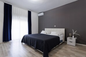 Ein modernes Schlafzimmer mit einem großen Bett, einem Nachttisch und einem Fenster mit Vorhängen.