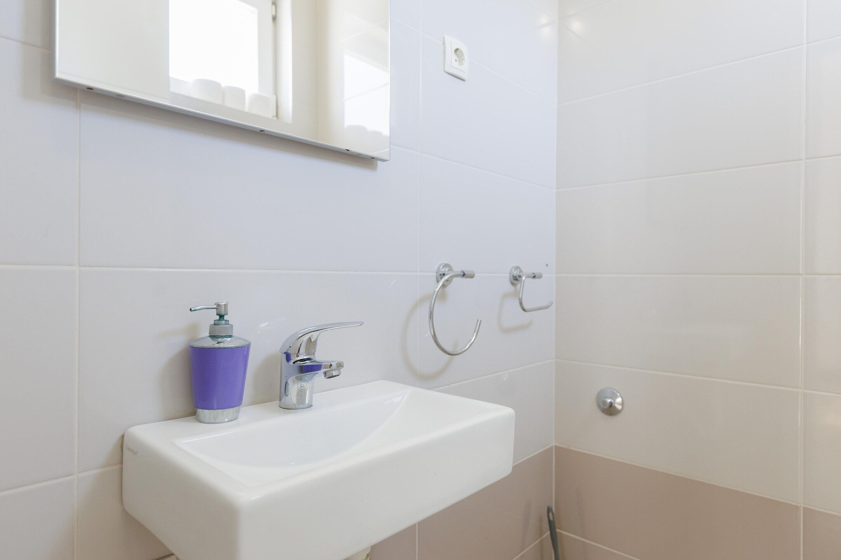 A bathroom with a white sink, a mirror, and a towel rack.