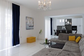 A modern living room with a grey sofa, a glass coffee table, and a chandelier. - Holiday Home in Galovac With Pool (Galovac)