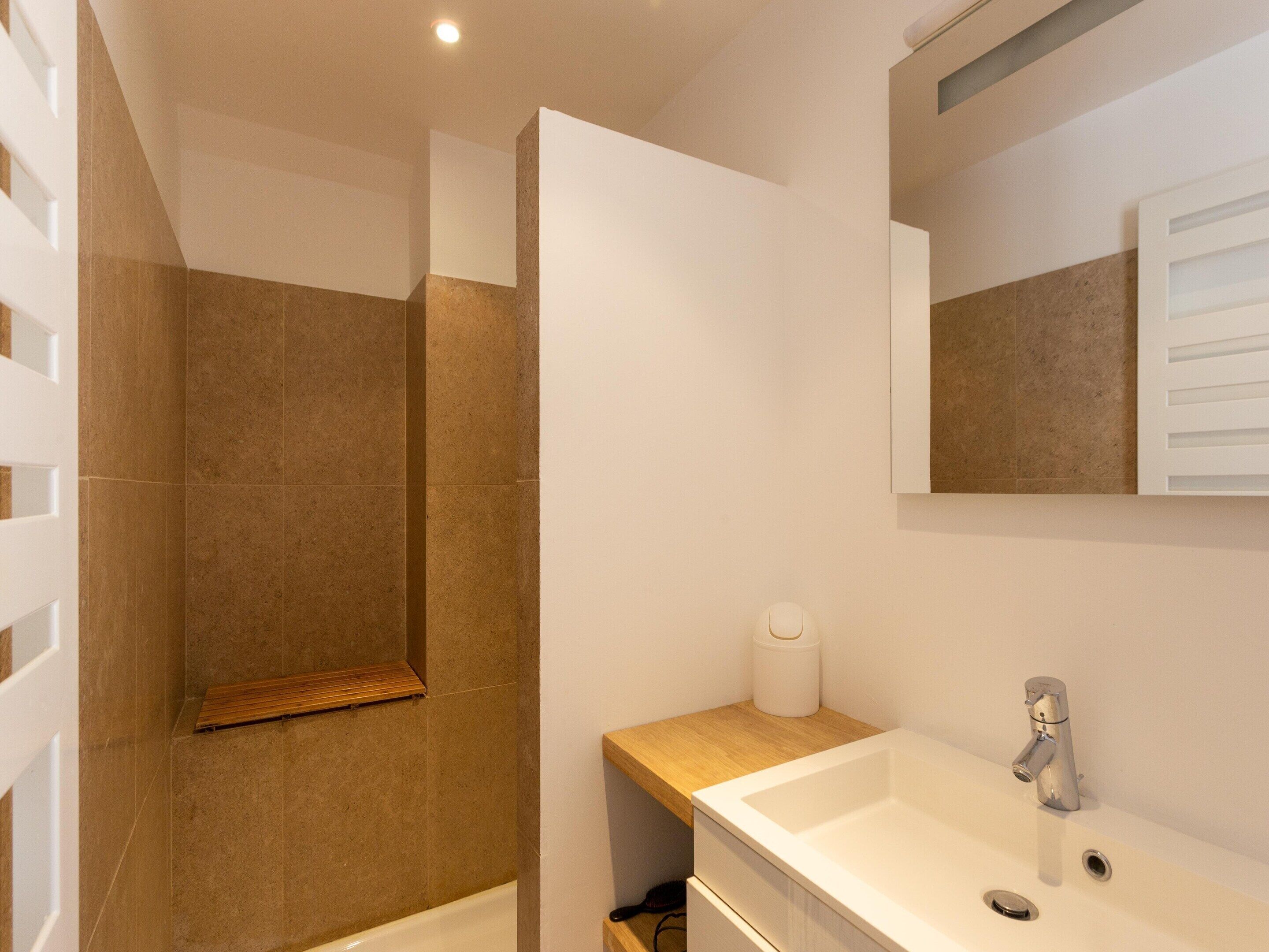 Une salle de bain moderne avec une douche, un lavabo et un miroir.