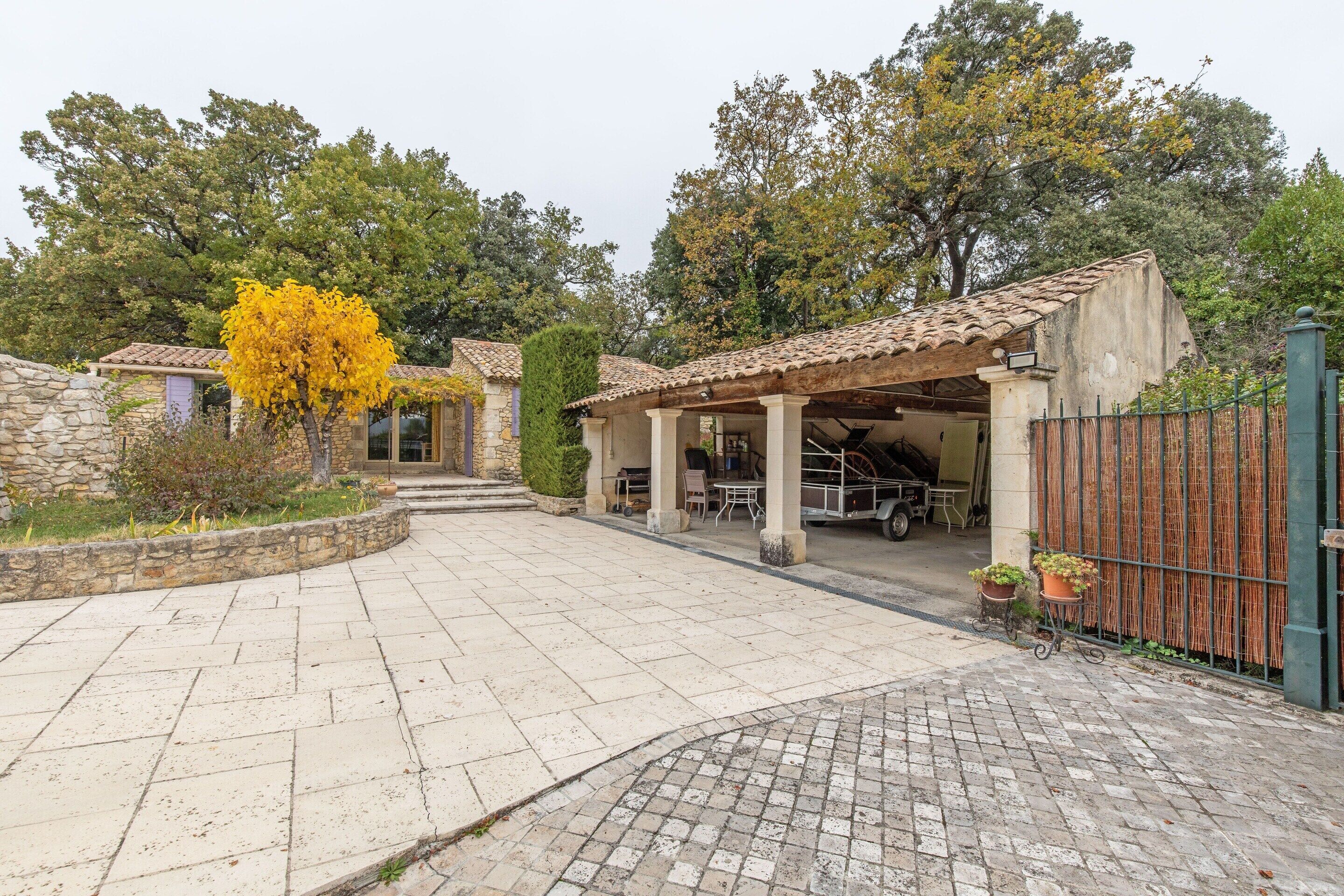 A courtyard with stone walls, a covered seating area, and a vehicle in the background.