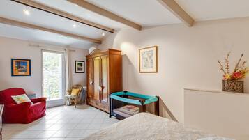 A bedroom with a bed, a red chair, a wooden wardrobe, and a window.