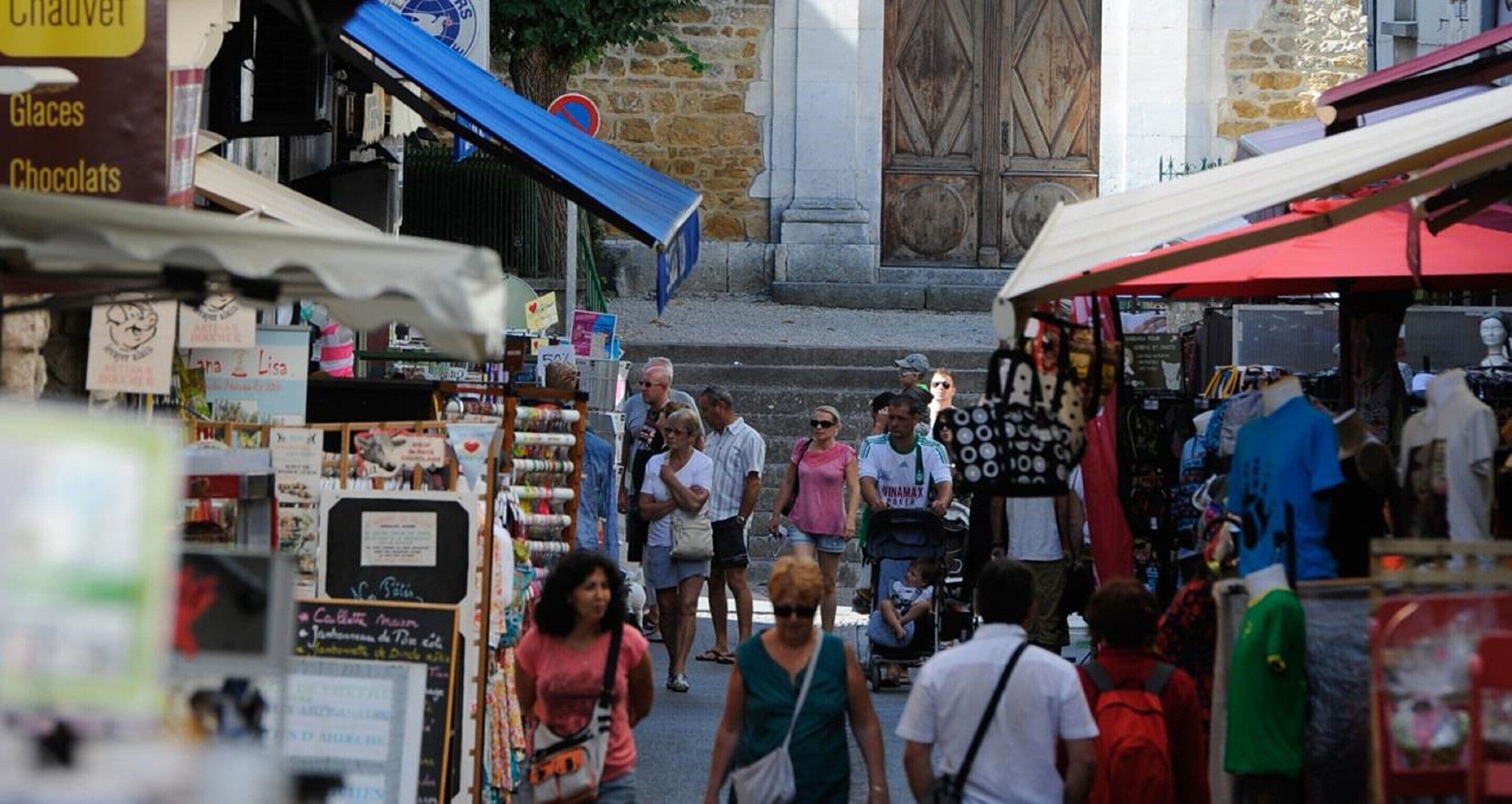 A bustling outdoor market with various stalls and people walking.