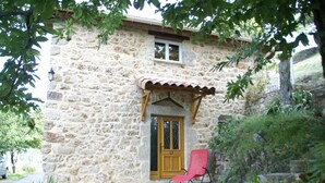 A stone building with a wooden door, a window, and a red chair outside. - House in Ardeche Near Ray-pic Falls (Saint-Pierre-de-Colombier)