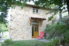 A stone building with a wooden door, a window, and a red chair outside. - House in Ardeche Near Ray-pic Falls (Saint-Pierre-de-Colombier)