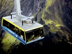 A cable car with "AHORNBACH" and "Mayrhof" logos, suspended over a mountainous landscape. - Spacious Apartment in Ramsau im Zillertal near Ski Area (Ramsau im Zillertal)