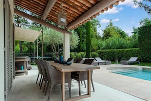 A covered outdoor area with a pool, a table with chairs, and a lounge chair. - Villa in Gassin Near Saint Tropez Beaches (Gassin)