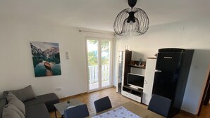 Ein moderner Wohnbereich mit Essplatz, einer Couch, einem Fernseher und einem Kühlschrank.