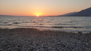 Ein Kiesstrand mit Sonnenuntergang über dem Wasser.