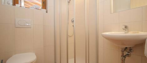Un baño con inodoro, cabina de ducha y lavamanos.