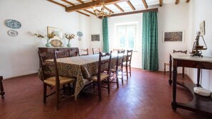 Un comedor con mesa y sillas de madera, una araña y una ventana con cortinas.
