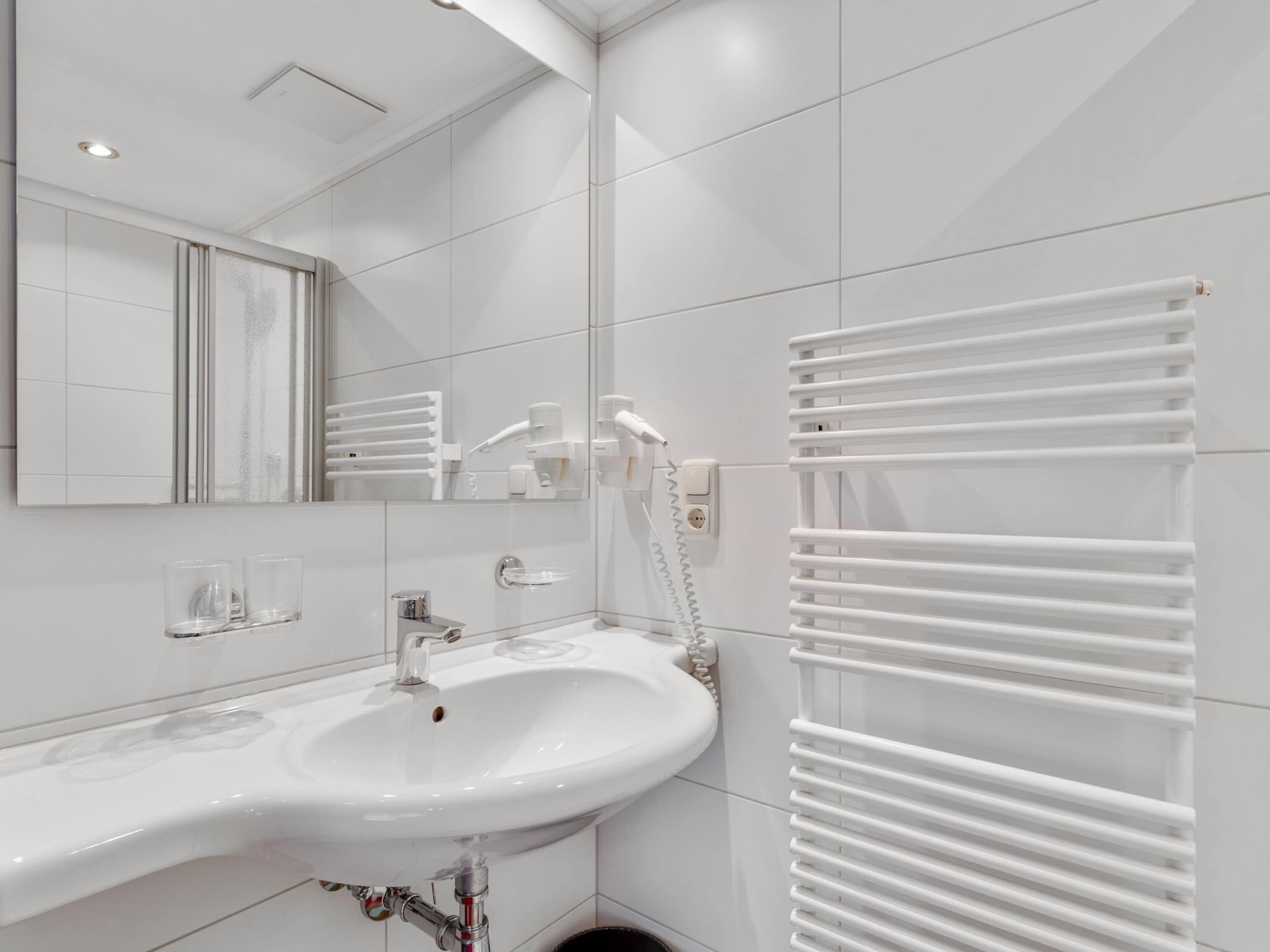 A modern bathroom with a white sink, mirror, and towel rack.