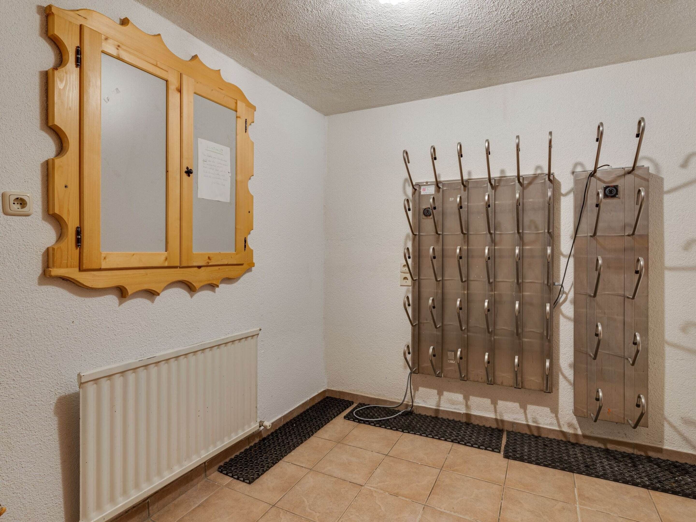 Une pièce avec une armoire en bois, un radiateur et un porte-manteau muni de crochets.