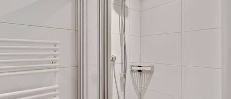 Een moderne douche met een handdouche en een bedieningspaneel aan de muur.