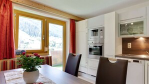 Ett modernt kök med vita skåp, en inbyggd ugn och ett fönster med utsikt över ett snötäckt landskap.
