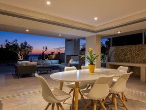 An outdoor dining area with a round table and chairs, a potted plant, and a stone wall.