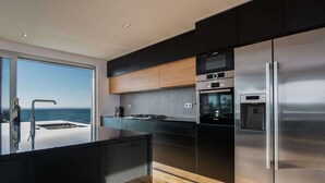 A modern kitchen with a large island, stainless steel appliances, and a view of the sea. - Luxurious Villa in Kozino With Fenced Garden (Zadar)