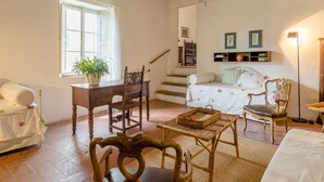A cozy living room with a wooden table, chairs, a sofa, and a staircase leading to another room. - Italian Stay: Bacchereto Wine Country (Carmignano)