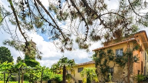 A courtyard with potted plants, a pergola, and a building with a tiled roof. - Rustic Farmhouse Stay, Carmignano (Carmignano)